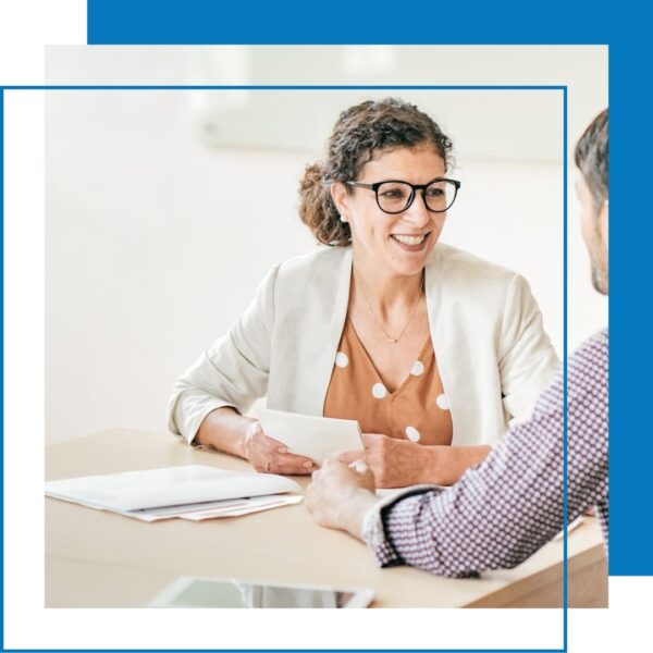 woman in blazer smiles at person sitting beside her