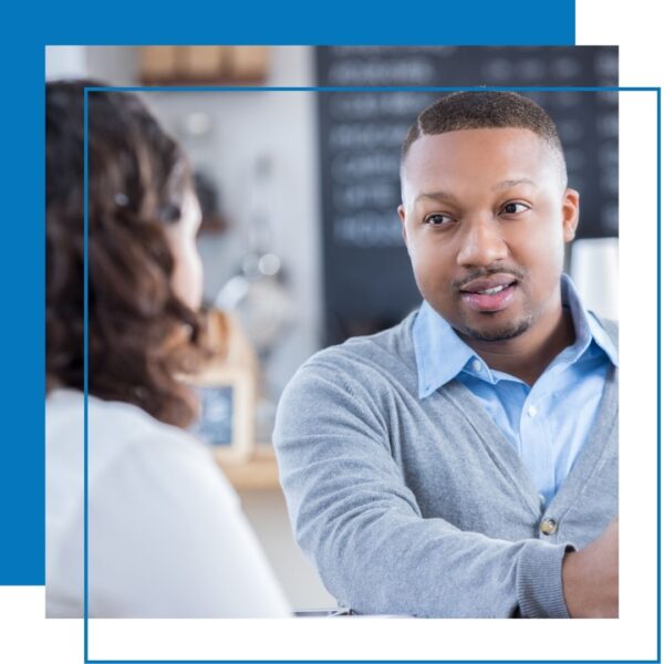 man in cardigan sweater looks at woman 
