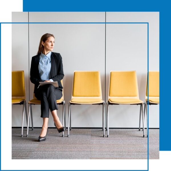 person in pant suit sits in waiting area chair
